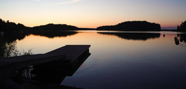 une jetée reflétée dans l’eau calme à empreintes de coucher de soleil, humides sur la jetée - lakedistrict photos et images de collection