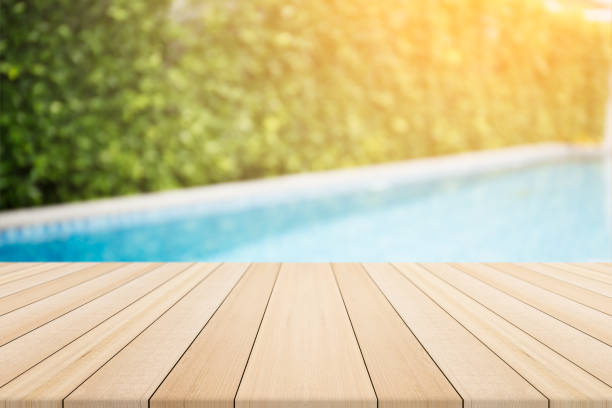 istock Empty wooden table in front with blurred background of swimming pool 833361150