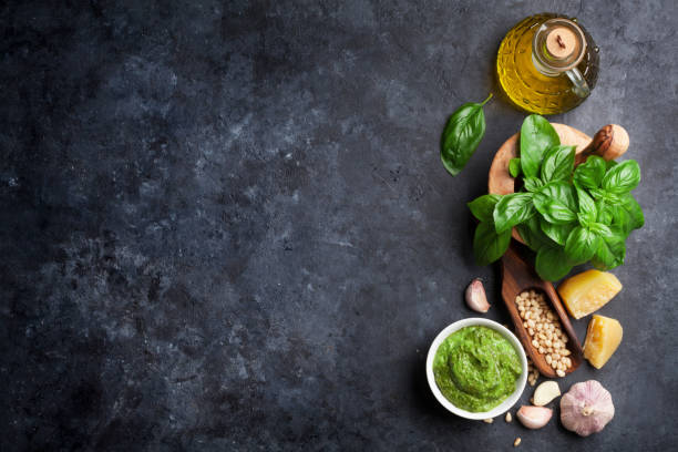 Pesto sauce ingredients Pesto sauce cooking. Basil, olive oil, parmesan, garlic, pine nuts. Top view on dark stone table with copy space for your text italian food photos stock pictures, royalty-free photos & images