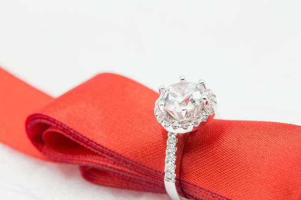 istock Diamond wedding rings in the Red ribbon on white. selective focus 833370608