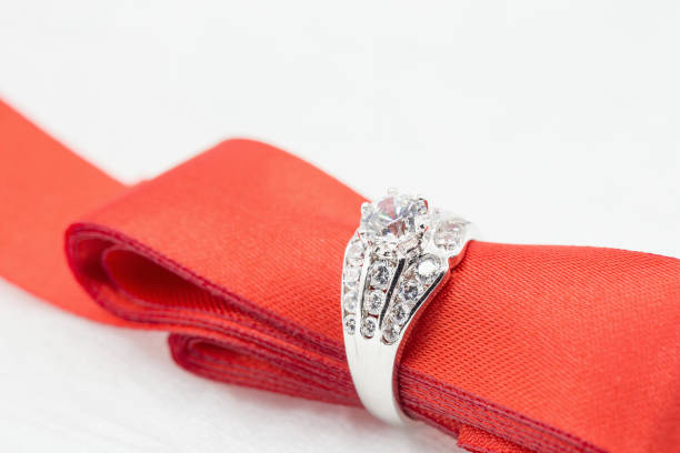 istock Diamond wedding rings in the Red ribbon on white. selective focus 833370732