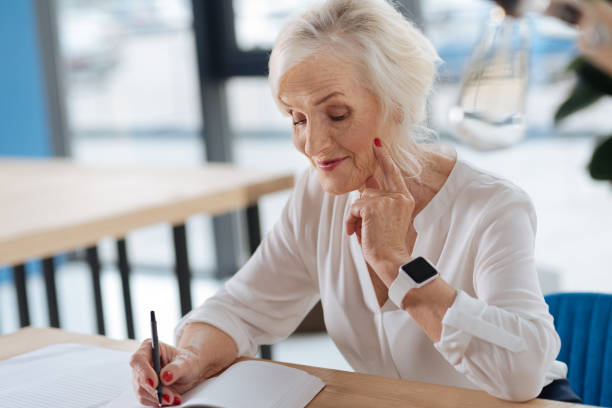 Happy aged woman writing down her memories