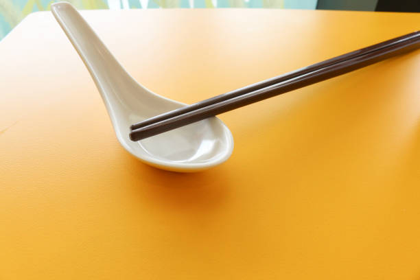 Hand holding chopsticks, isolated on white background.