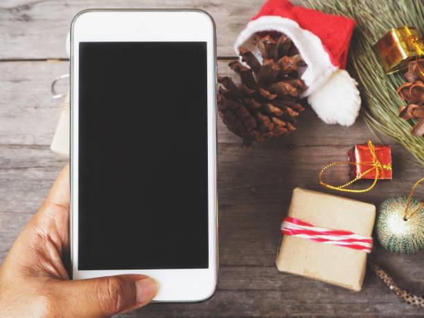 istock Smart phone on hand and pine cone with christmas hat and gift 833390434