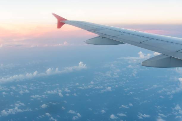 istock Airplane wing from window seat at sunset with clouds. 833390542