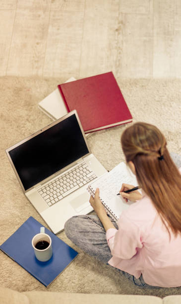 istock Young student learning at home, sitting on carpet in living room. 833393304