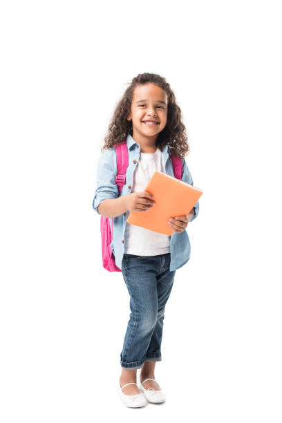 piękna afroamerykańska uczennica trzymająca podręcznik i uśmiechająca się do kamery odizolowanej na białym - schoolgirl child backpack book bag zdjęcia i obrazy z banku zdjęć