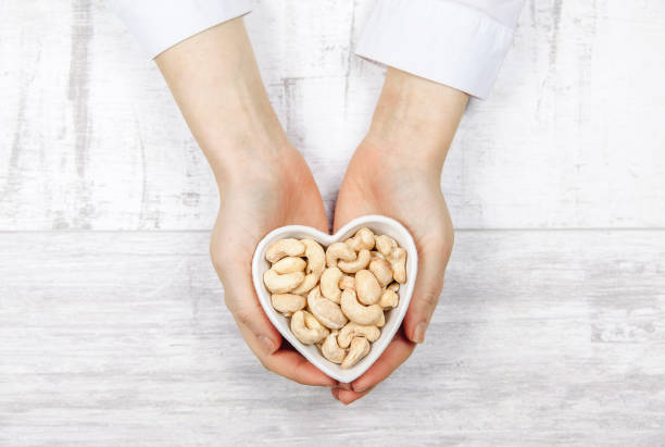 Caucasian woman holding cashew nuts in a heart shaped stock photo