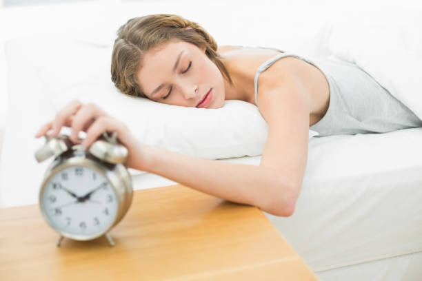 istock Exhausted young woman turning off the alarm clock 833459456
