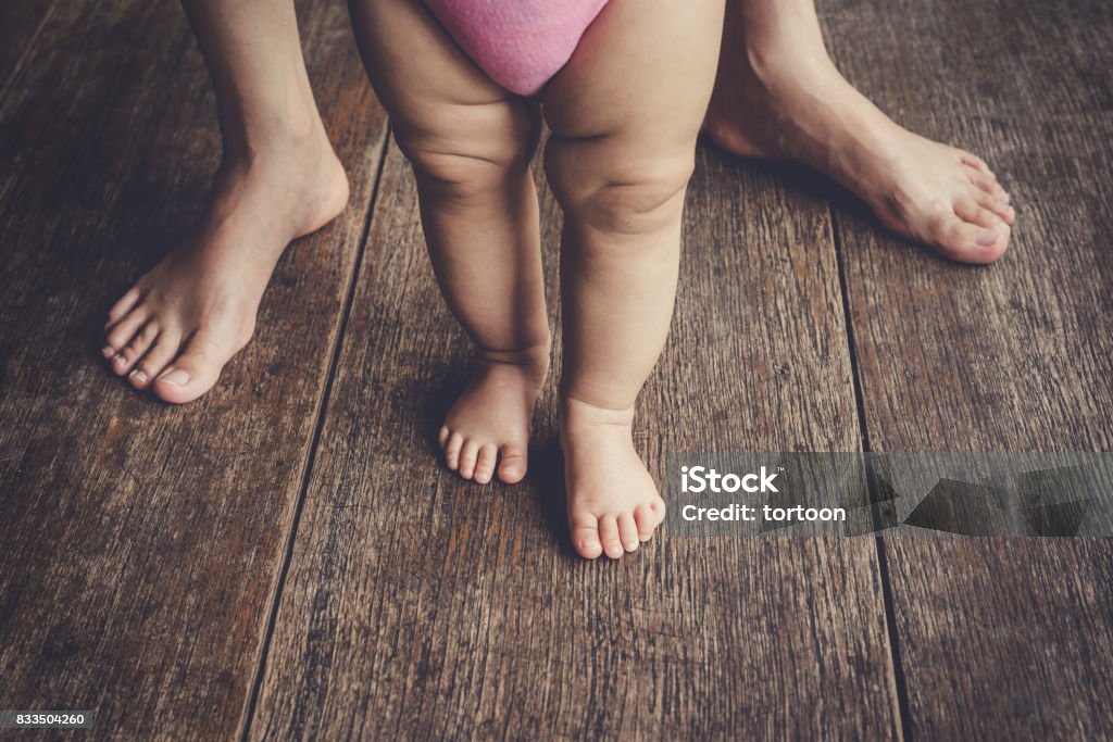 happy baby learning to walk with mother help Adult Stock Photo