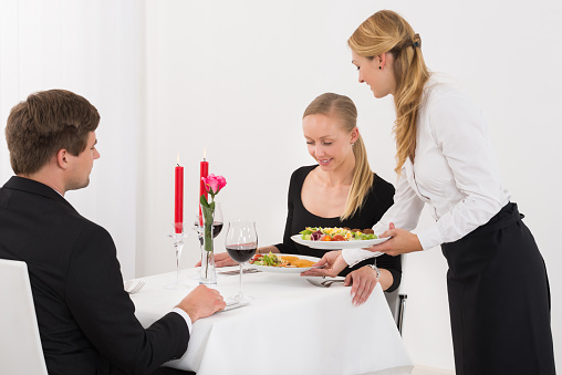 Female Couple Serving Food To Young Couple In Restaurant