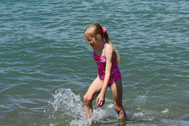 Full length image of pretty young girl in bikini with fins and luggage on white background