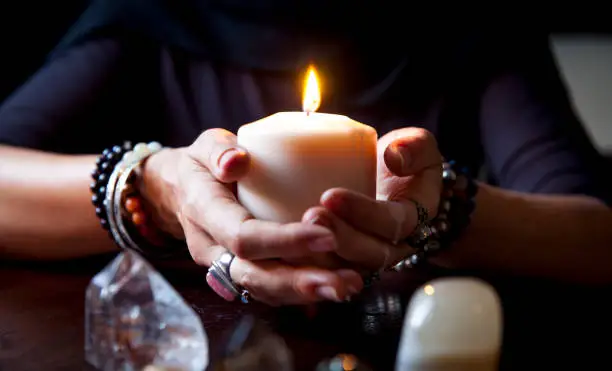 female hands holding a burning candle