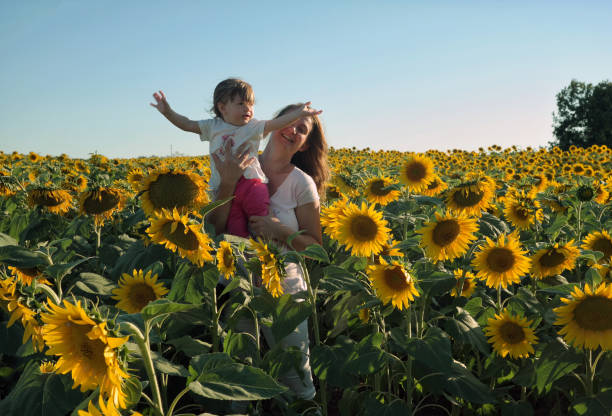 istock Mother and daughter enjoy in a sunflower field. 833598024
