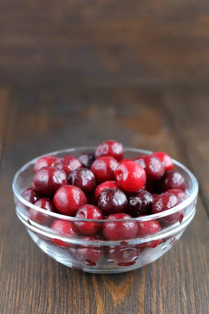 Sweet cherries in glass bowl on wooden table. Juicy ripe cherries for healthy eating.