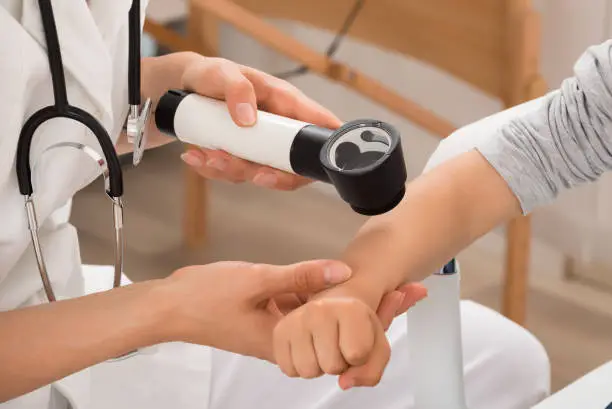 Close-up Of Doctor Examining Skin Of Child Patient With Dermatoscope