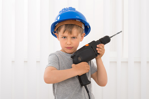 Portrait Of A Boy In Hard Hat Holding Electric Drill