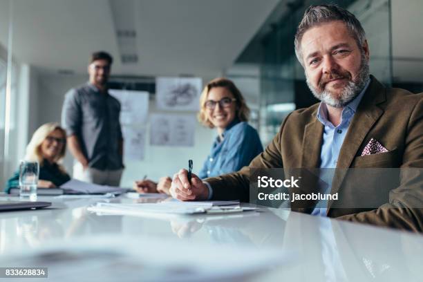 Businesspeople Looking At Camera With Smile Stock Photo - Download Image Now - Senior Adult, Business Meeting, Business