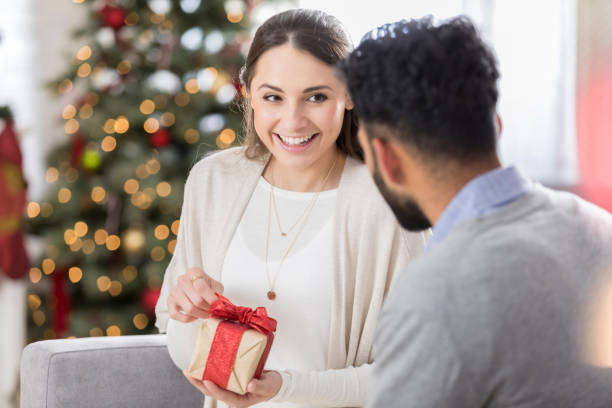 istock Young woman teasingly opens friend's Christmas gift 833666134