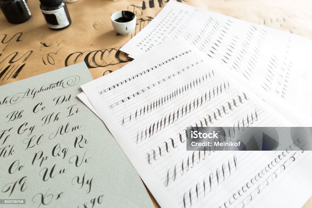 calligraphie, l’éducation, le concept de design graphique. beaucoup d’exercices pour les compétences de la formation de la calligraphie avec l’aide de fournitures spéciales comme l’encre noire, des pinceaux et des feuilles blanches lignées - Photo de Calligraphie libre de droits