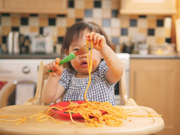 istock baby girl eating messy spaghetti 833747608