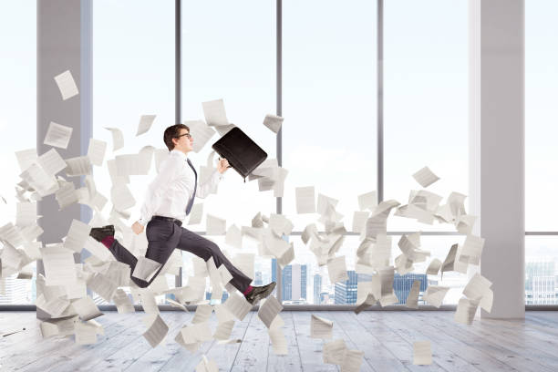 istock Businessman jumping in an office lobby, papers 833757562