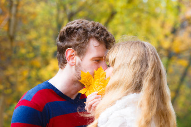 istock couple with maple leaf kissing in autumn park 833764738