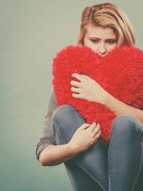 istock Sad woman holding red pillow in heart shape 833765180