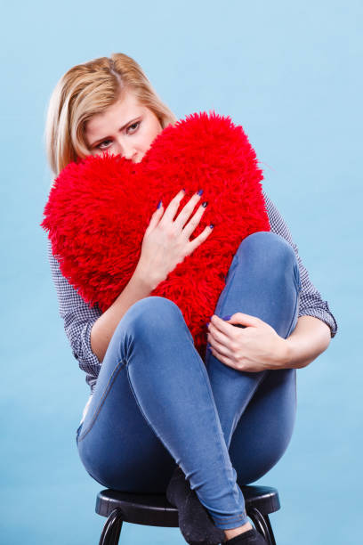 istock Sad woman holding red pillow in heart shape 833765368