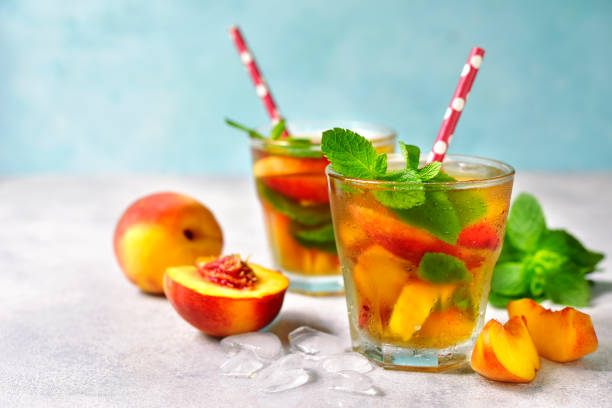 Peach iced tea with mint Peach iced tea with mint in a glass on a light background. mint julep photos stock pictures, royalty-free photos & images