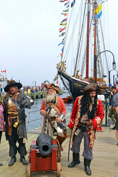 Halifax, Nova Scotia, Canada - July 29, 2017:  Members of the Pirates of Halifax troupe pose with tourists in front of The Bluenose at the Tall Ships event.