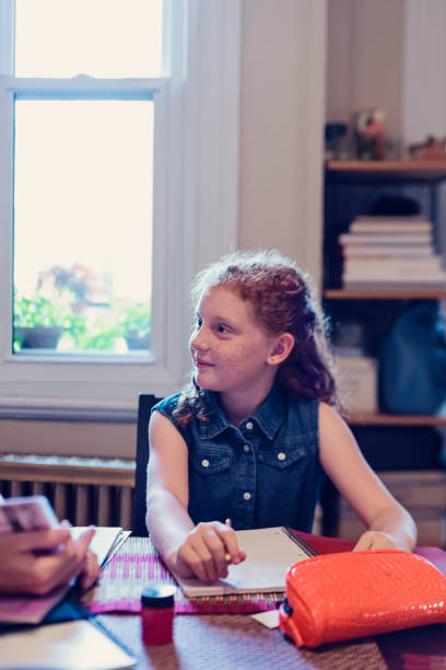 istock Young expressive redhead girl doing school homework at home. 833884678