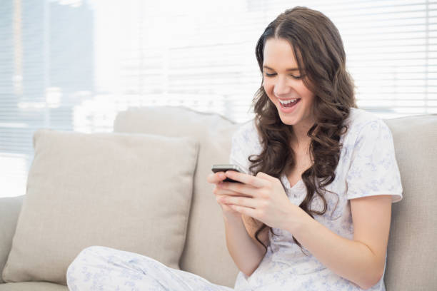 istock Smiling pretty woman in pyjamas reading a text on her smartphone 833974420