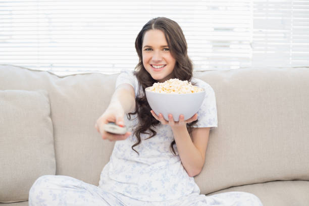 istock Pretty woman in pyjamas having popcorn while watching tv 833975096