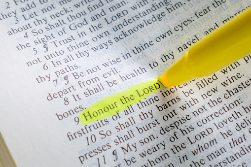 Open bible page with a portion of scripture highlighted with a marker that shows 'Honour the Lord'.