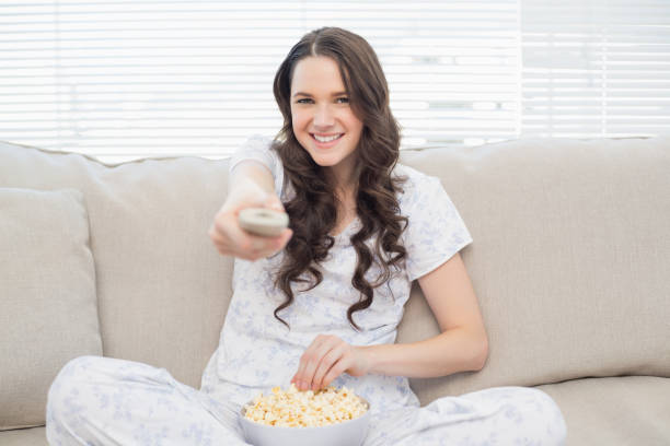 istock Cheerful woman in pyjamas having popcorn while watching tv 833975212