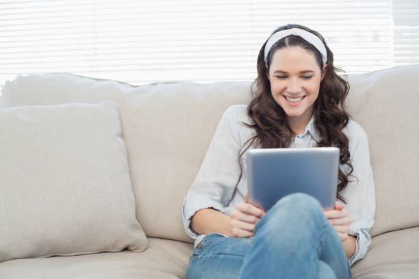 istock Casual woman on cosy couch using tablet pc 833975850