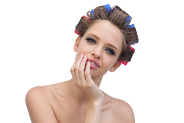 istock Cheerful model in hair curlers posing with hand on her face 833992162