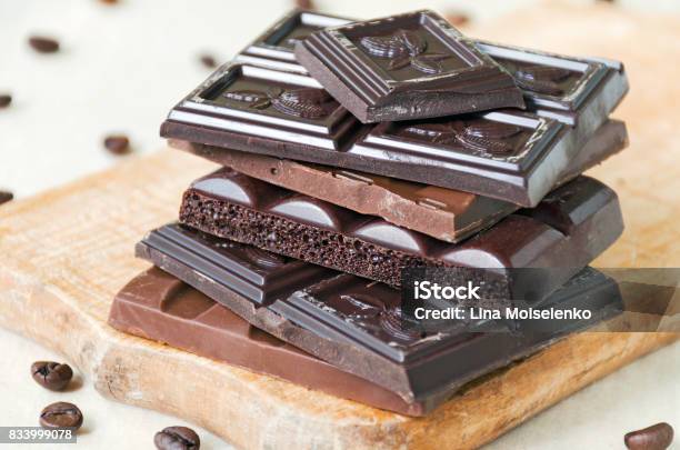 Broken Chocolate Bars Of Different Kinds Of Chocolate Are Stacked On A Wooden Board Around A Bit Of Coffee Beans Stock Photo - Download Image Now