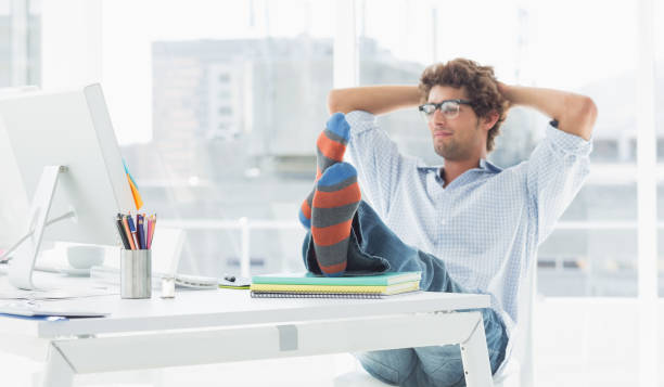 istock Casual young man with legs on desk in office 834022702