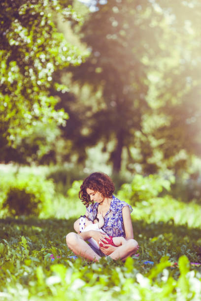 Young mother breast feeding a baby in the park stock photo