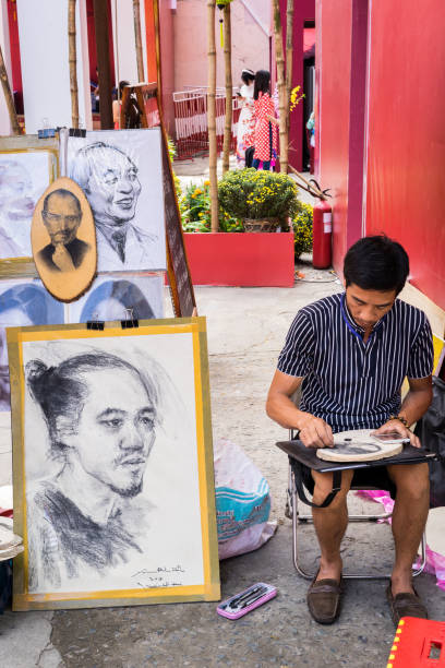 Man artist at spring fair on happy new year Hochiminh city, Vietnam - Jan 26 2017: Caricature Artist drawing in district 1. Artists line the resort during the summer for tourists to take back as souvenirs. vietnamese old man portrait stock pictures, royalty-free photos & images