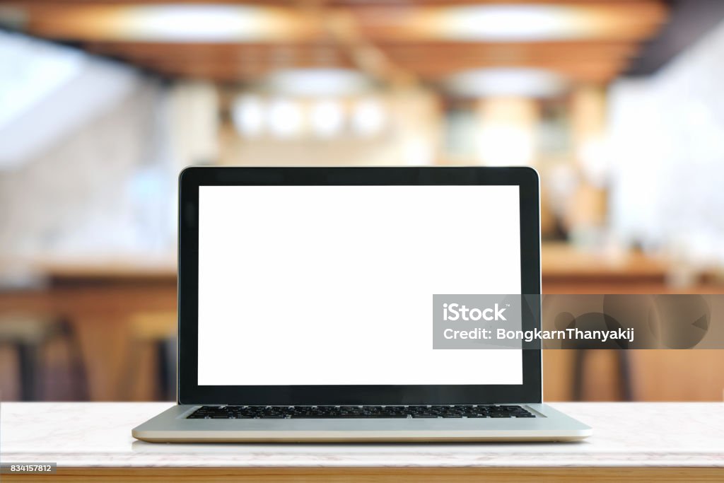 Mock up Blank screen of Laptop on marble table in Co-working or cafe. Laptop Stock Photo