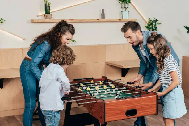beautiful young family family playing table football in cafe