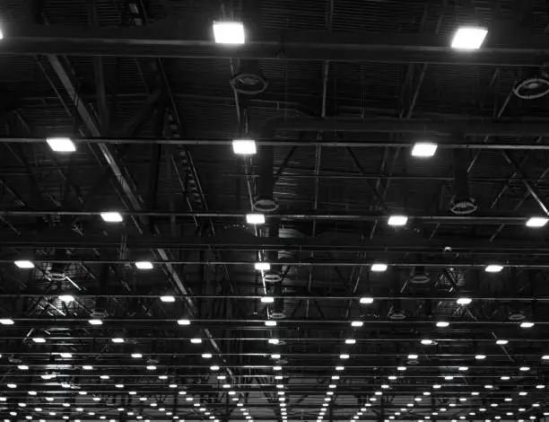 Photo of Lights and ventilation system in long line on ceiling of the dark office industrial building, exhibition Hall Ceiling construction