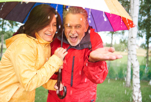 qu’ils profitent pleinement - umbrella senior adult couple autumn photos et images de collection