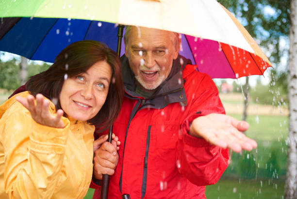 istock Senior couple under rainbow umbrella catching raindrop 834255682