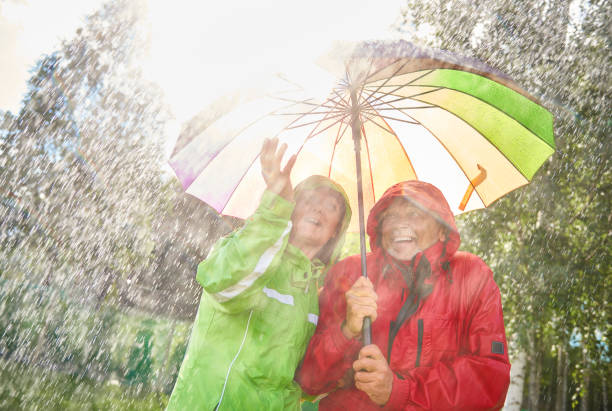 happy couple standing with umbrella - umbrella senior adult couple autumn imagens e fotografias de stock