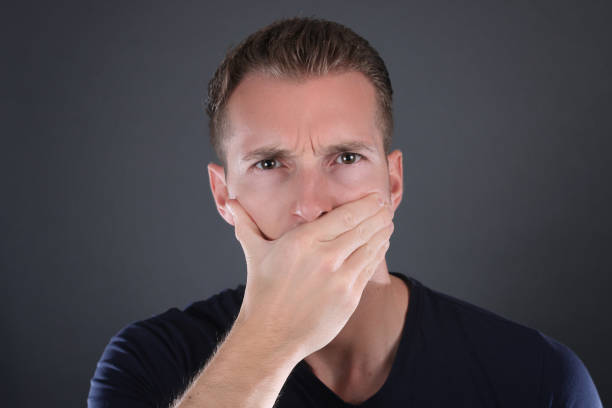 istock man covering his mouth - speak no evil concept. 834268410