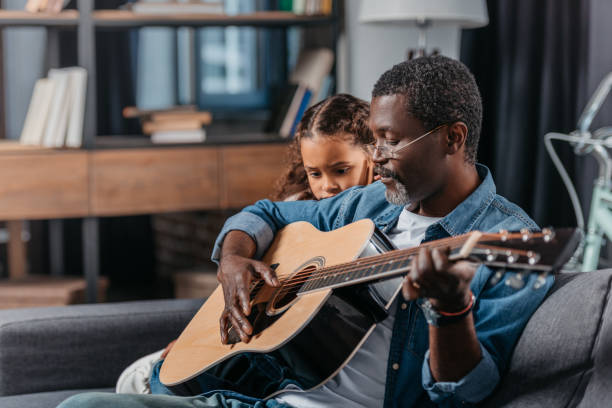 istock man playing guitar with daughter at home 834330016